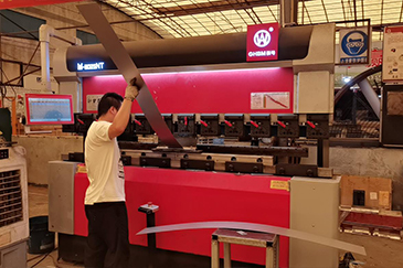 Worker at a sheet-metal press brake in the manufacturer's workshop